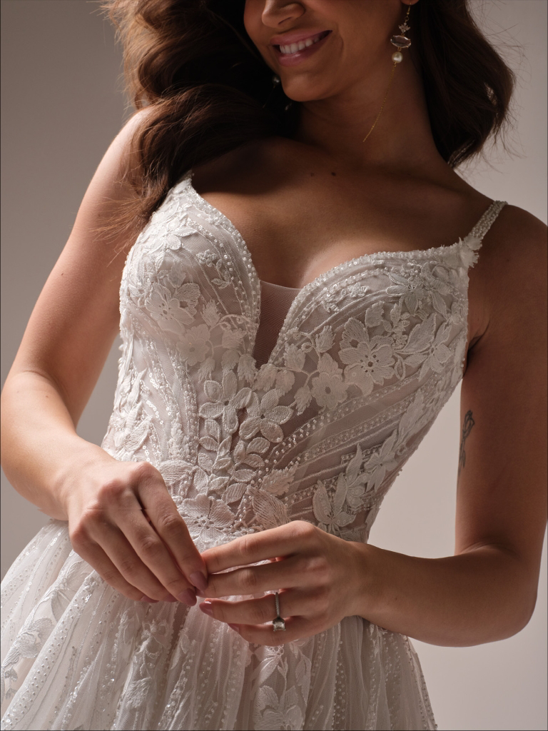 Bruidsjurk met V-hals Liberty van Maggie Sottero. Close-up van het kanten korsetlijfje en schouderbandjes met parels.