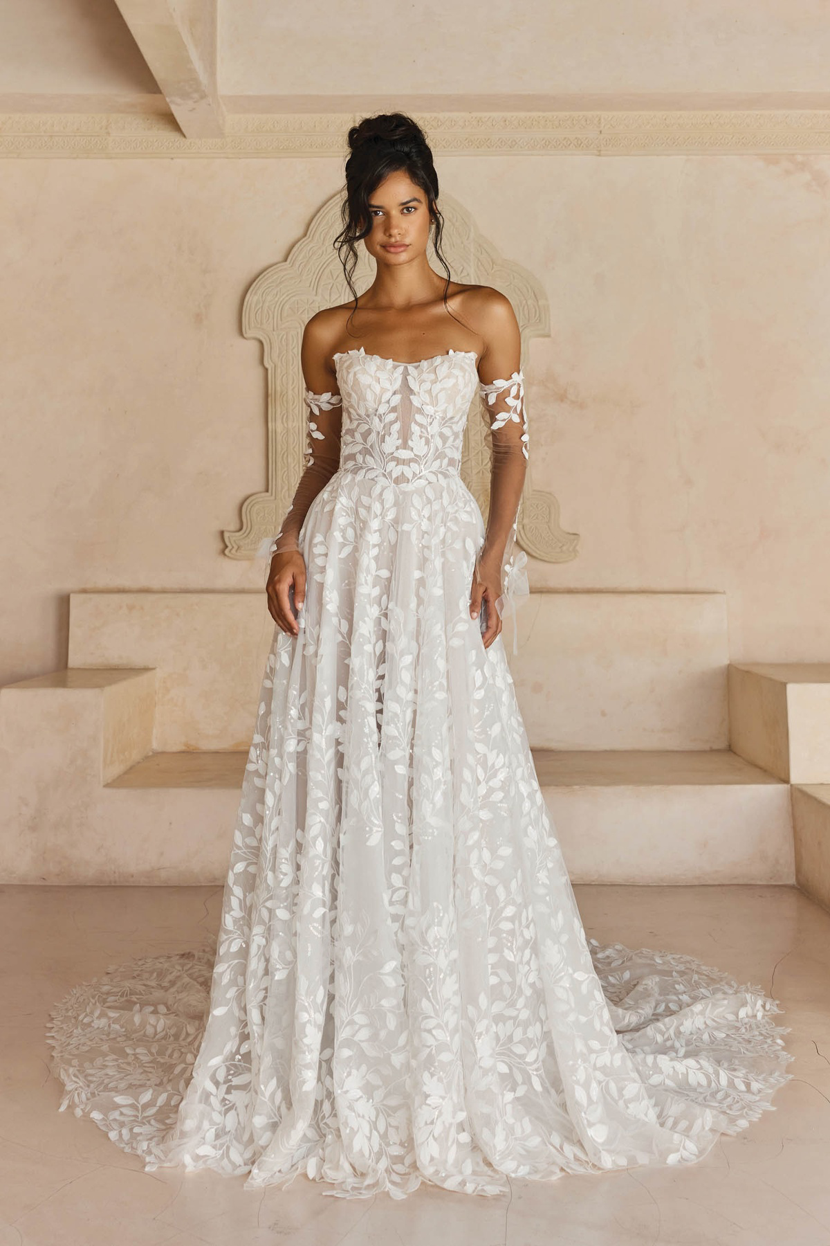 A-lijn trouwjurk Laiya van Madi Lane met off-shoulder mouwen en blaadjes kant. Vooraanzicht van de romantische bruidsjurk.