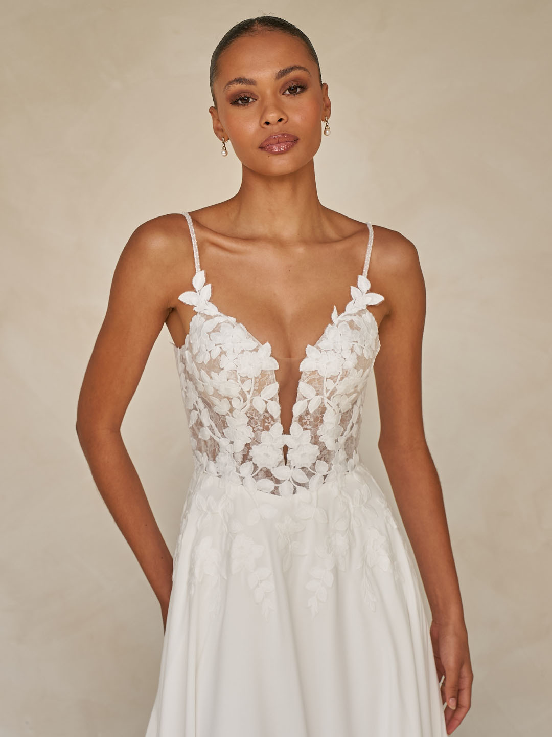 Trouwjurk Whyte van Madi Lane met diepe V-hals en 3D kant op een see-through lijfje. Close-up van de voorzijde.