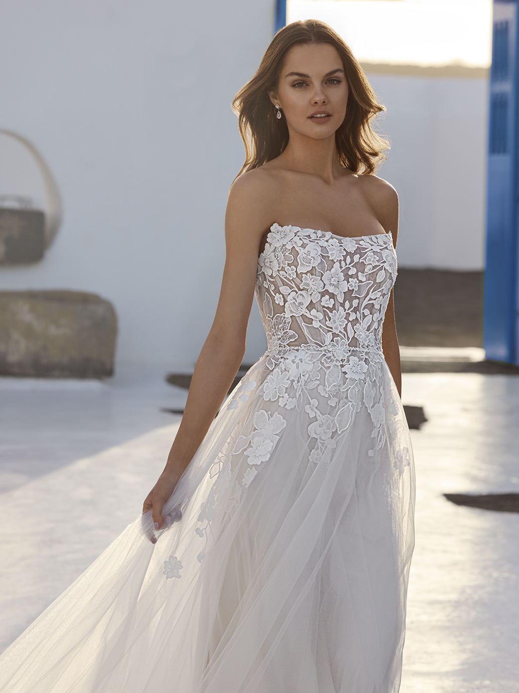 A-lijn trouwjurk Enola van Love by Enzoani met strapless see-through lijfje en 3D bloemenkant, vooraanzicht.