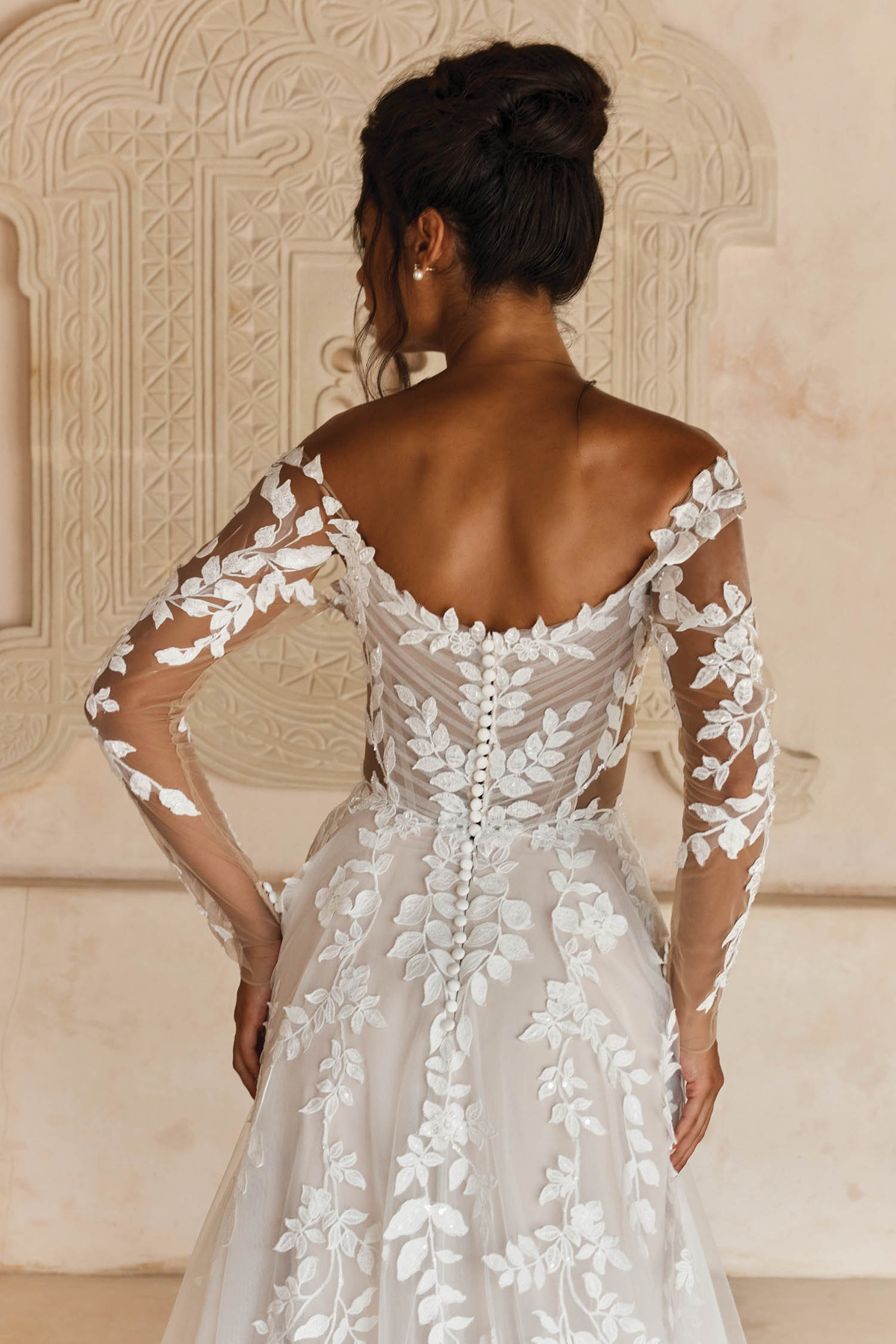 Bruidsjurk met lage rug Landon van Madi Lane, achteraanzicht met kanten lange mouwen en knoopjes.