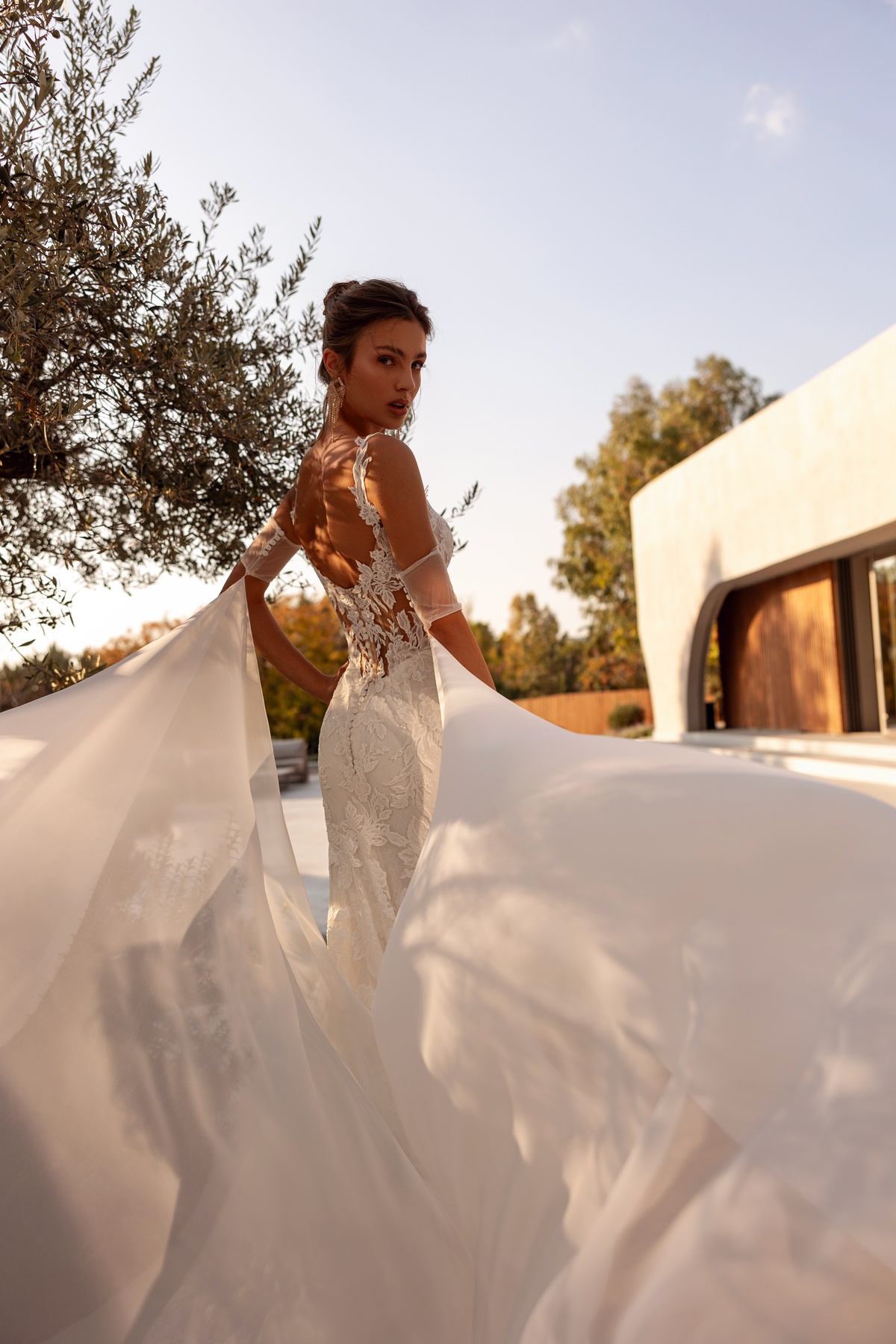 Bruidsjurk met lage rug 1516 van Demetrios in zeemeermin stijl. Achteraanzicht van de jurk met kanten details en flowy sleep.