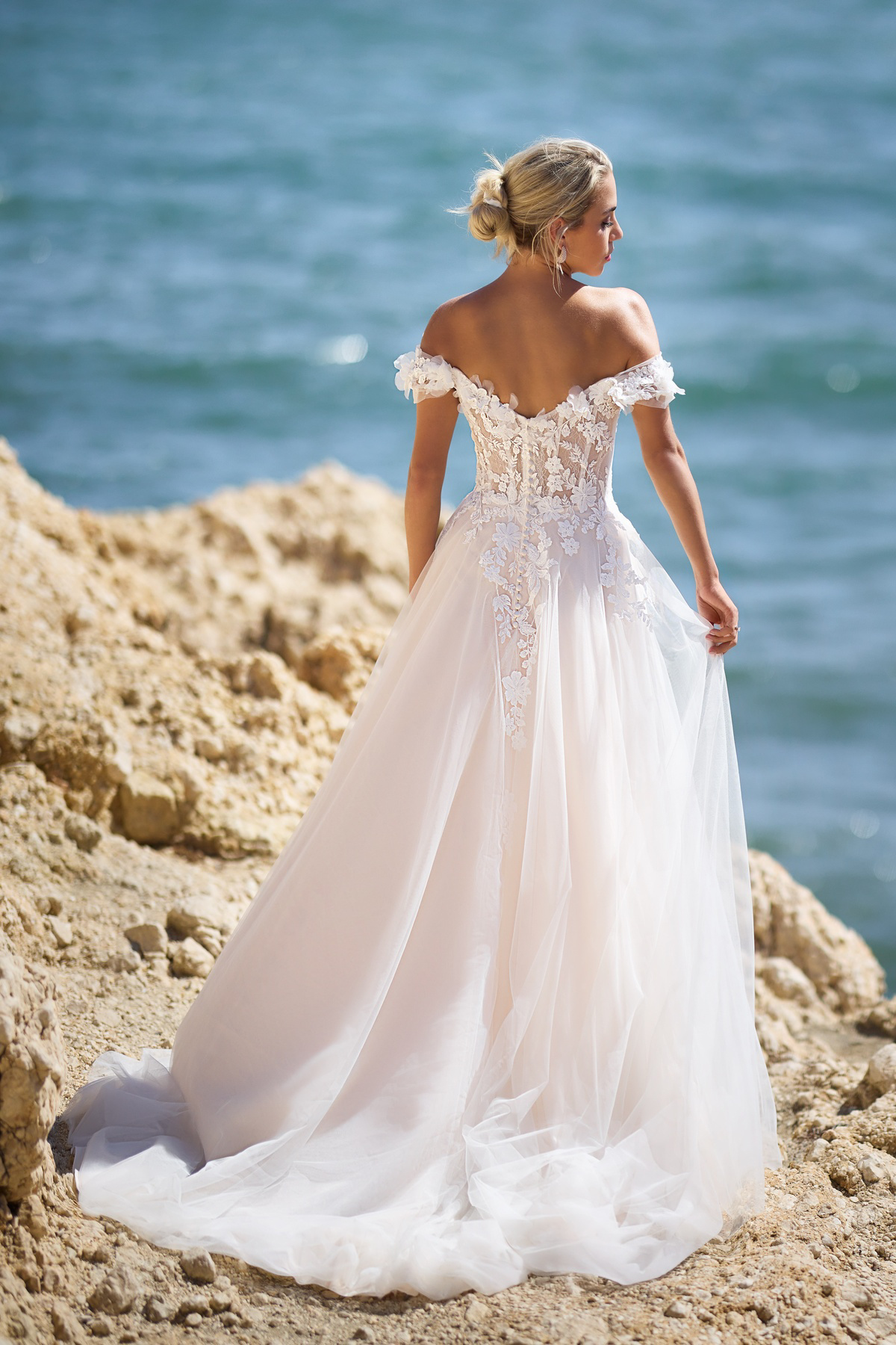 A-lijn trouwjurk 26112 van Tres chic achteraanzicht. Off-shoulder bruidsjurk met see-through lijfje en 3D kanten bloemen.