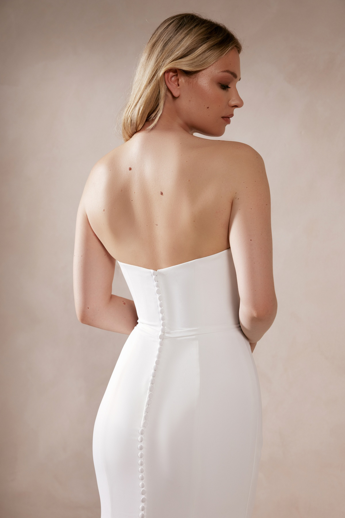 Strapless trouwjurk Deva van Adore met lage rug. Achteraanzicht van de aangesloten jurk met picpac knoopjes.