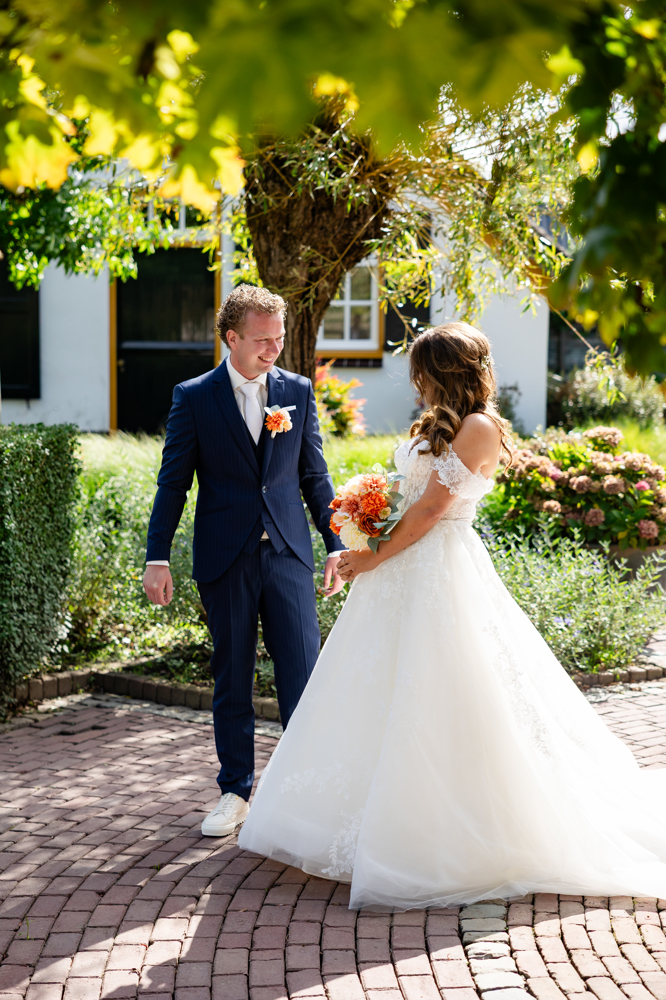 Bruid Birgit Arts lacht samen met haar bruidegom in het heideveld, zij draagt een romantische kanten trouwjurk van Bruidshuis Diana.