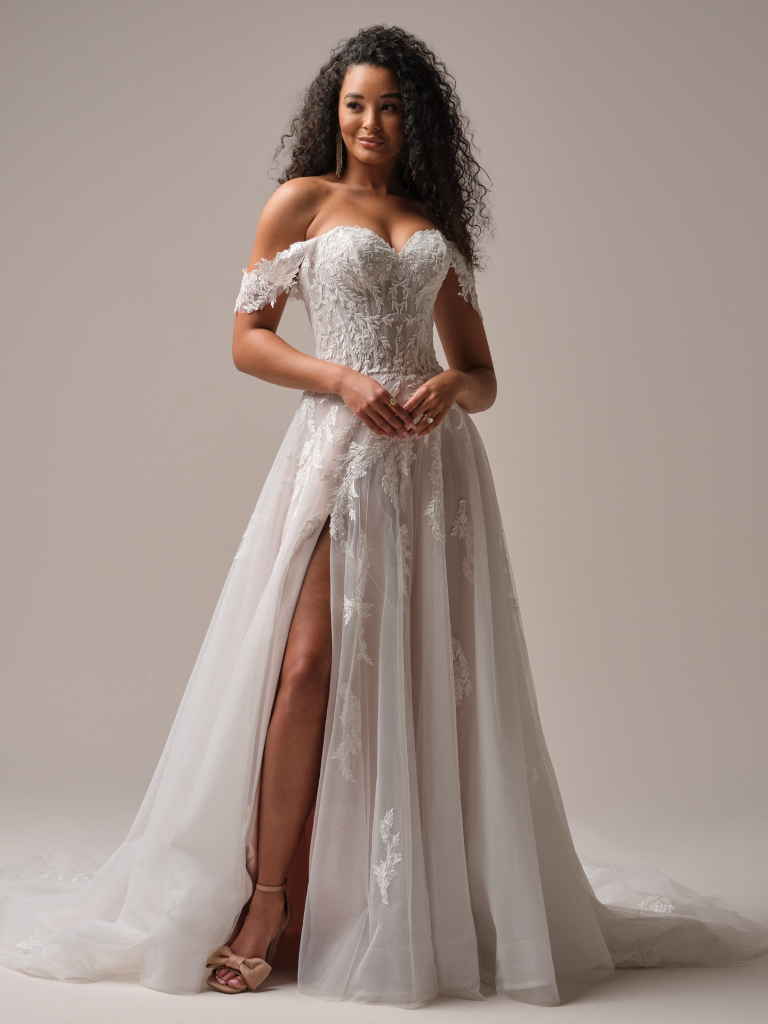 A-lijn trouwjurk Victoria van Maggie Sottero met split. Vooraanzicht van de off-shoulder bruidsjurk met kanten lijfje.