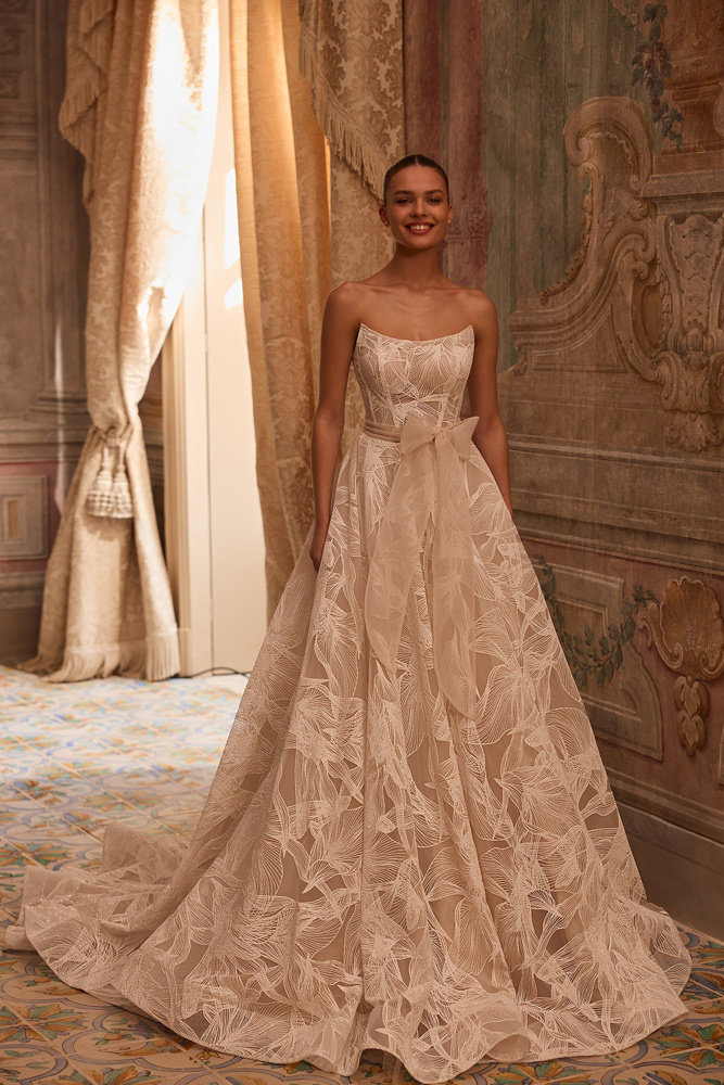 Strapless A-lijn trouwjurk Octavianna van Aria. Vooraanzicht van de romantische bruidsjurk met grote strik en bladmotief.