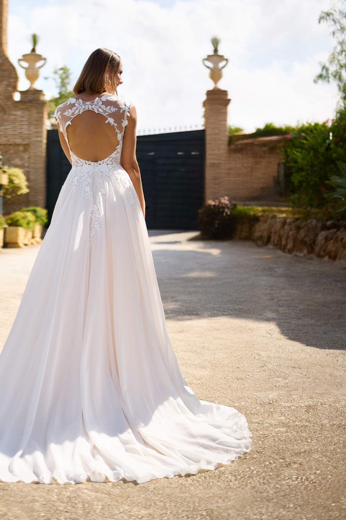 A-lijn trouwjurk met open rug 26115 van Tres chic. Achteraanzicht van de flowy chiffon rok en het kanten see-through lijfje.