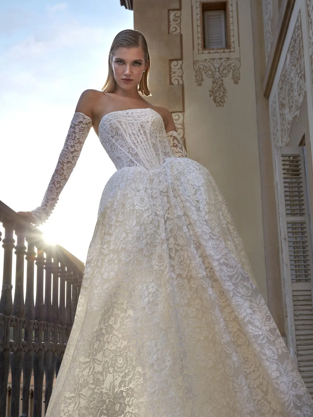 Kanten trouwjurk Beatris van Pronovias Privee. Vooraanzicht van de prinsessenjurk met strapless korsetlijfje en losse mouwen.