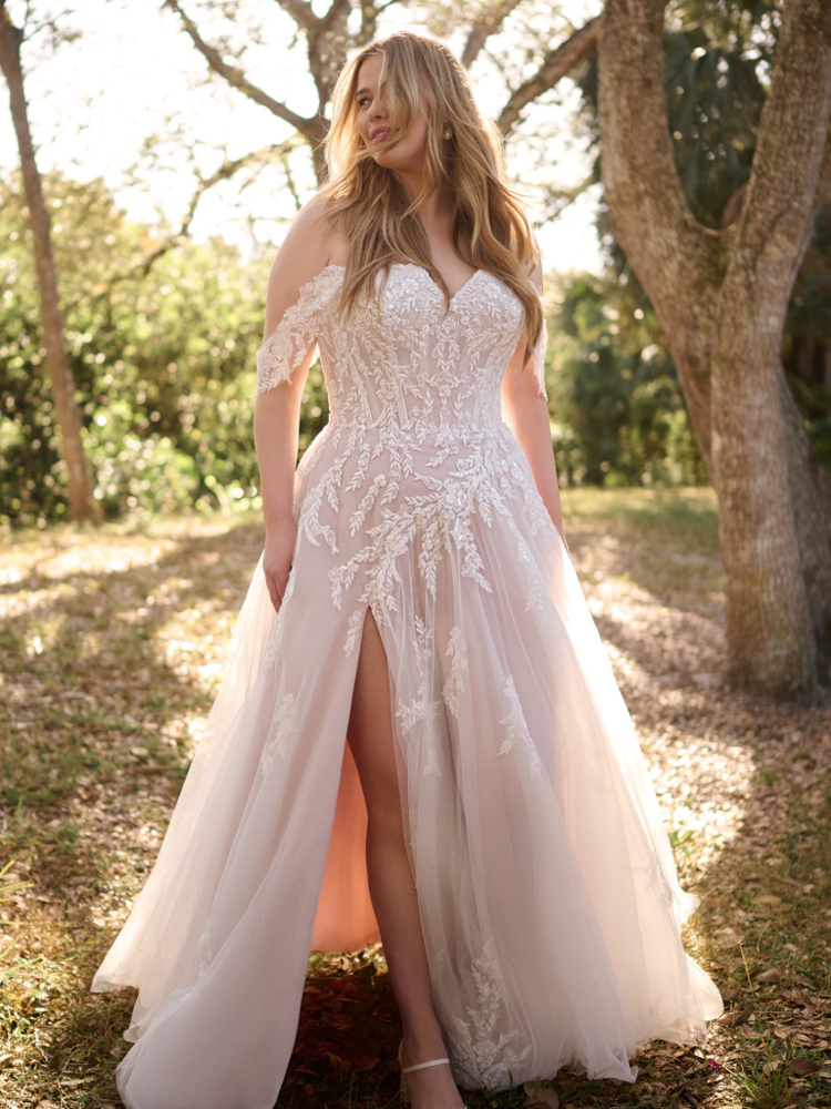 Trouwjurk met split Victoria Curvy van Maggie Sottero. Vooraanzicht van de A-lijn jurk met kanten off-shoulder bandjes.
