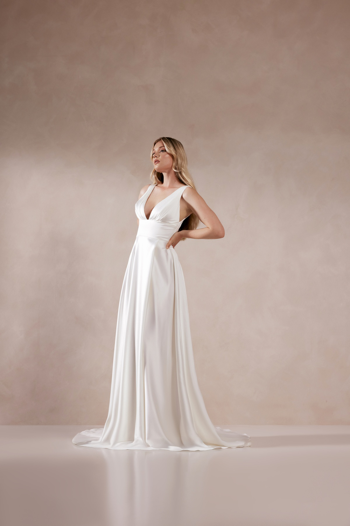 Minimalistische trouwjurk Phaedra van Adore in A-lijn. Zijaanzicht van de flowy satijnen bruidsjurk met diepe V-hals.