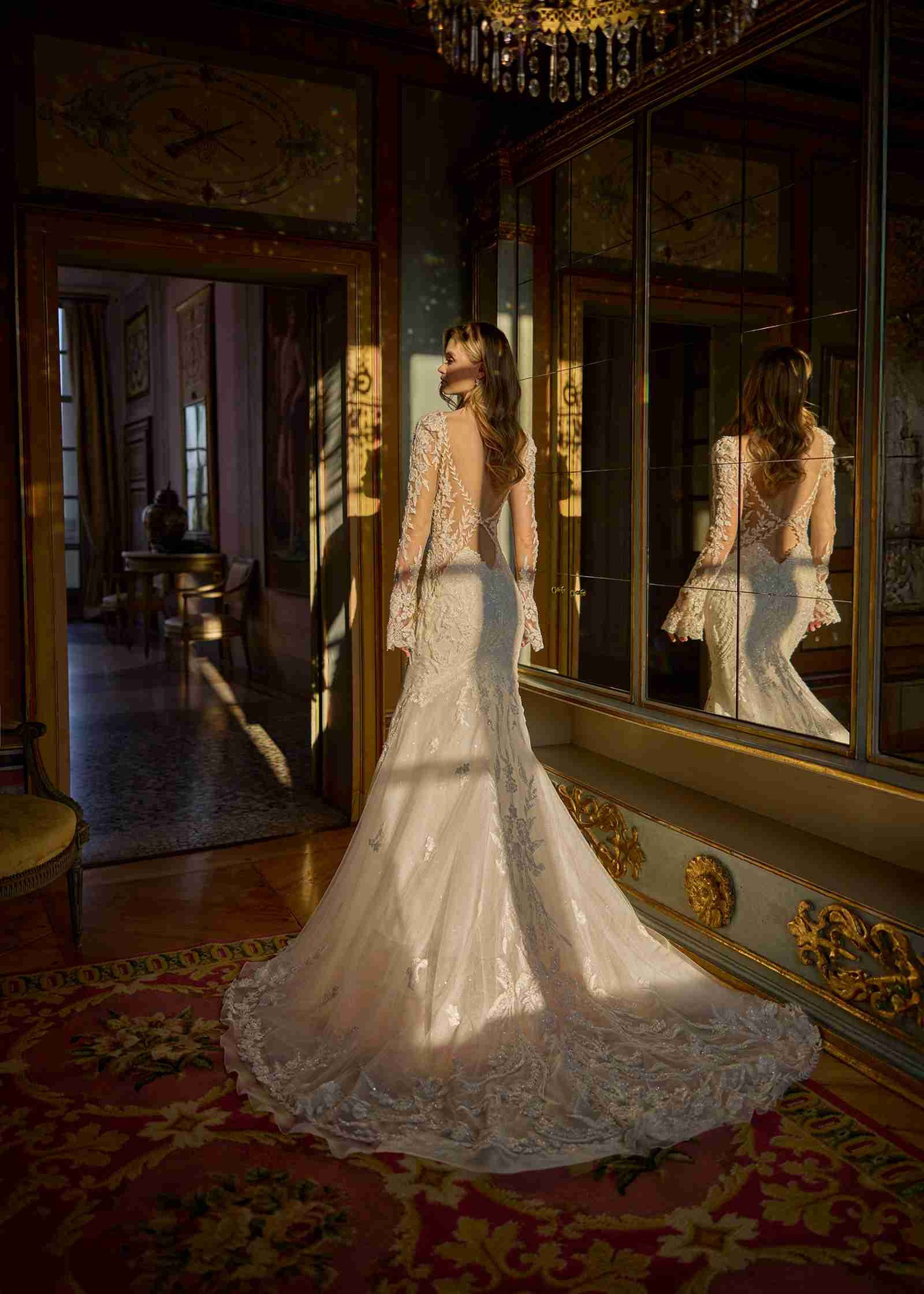 Trouwjurk met lage rug Juliana van Randy Fenoli. Achteraanzicht van de aangesloten jurk met lange kanten mouwen en sleep.