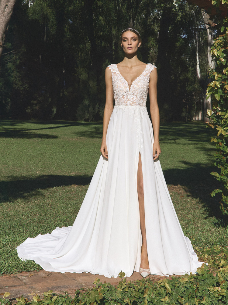 Trouwjurk met split Alguem van White one. Vooraanzicht van de A-lijn jurk met kanten V-hals lijfje en flowy rok.