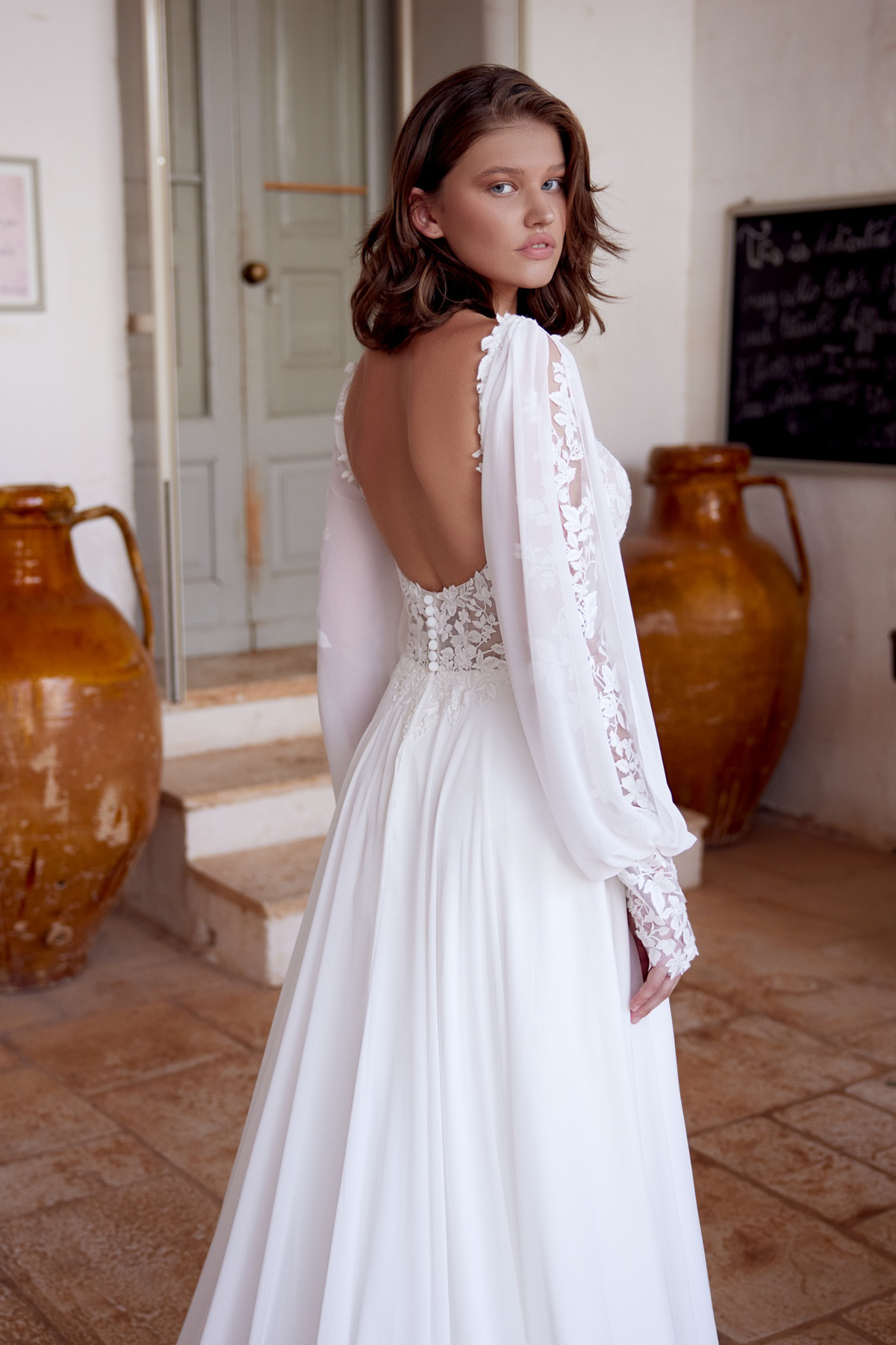 Trouwjurk met open rug 66391 Lillian West. Achteraanzicht van de bohemian A-lijn jurk met kanten, flowy lange mouwen.