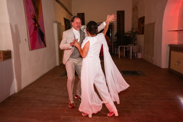 real-bride-review-daphne-de-laat-bruidshuis-diana – bruid Daphne de Laat danst samen met haar bruidegom tijdens het feest, haar soepel vallende jumpsuit met cape beweegt sierlijk mee