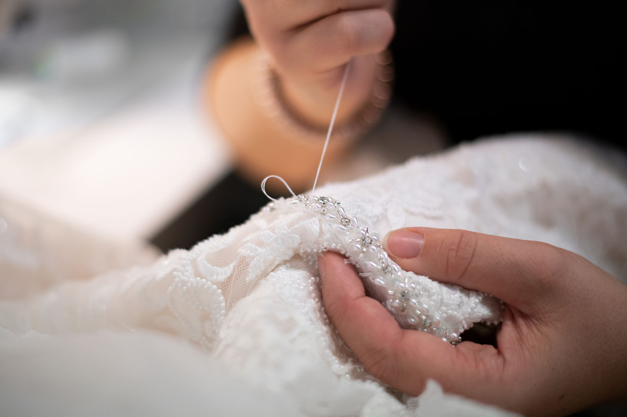 Coupeuse vermaakt een trouwjurk met de hand