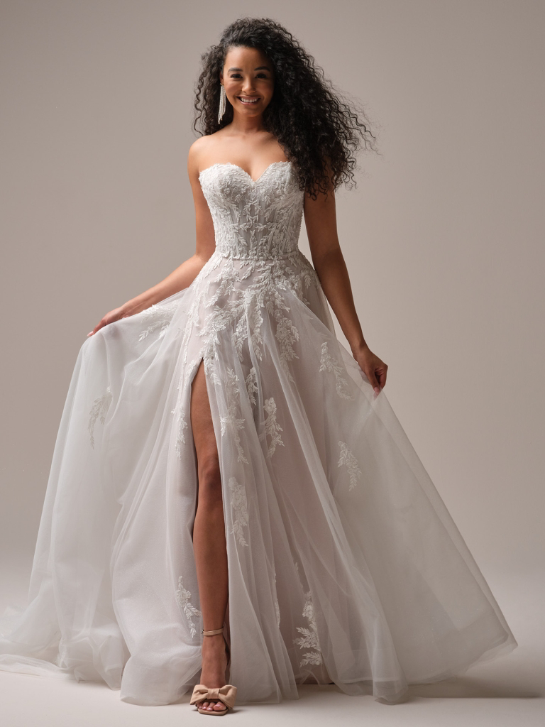 A-lijn trouwjurk Victoria van Maggie Sottero met split en kanten off-shoulder bandjes. Vooraanzicht van deze romantische jurk.