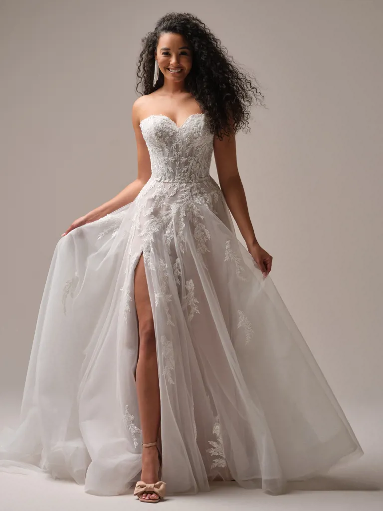 A-lijn trouwjurk Victoria van Maggie Sottero met split en kanten off-shoulder bandjes. Vooraanzicht van deze romantische jurk.
