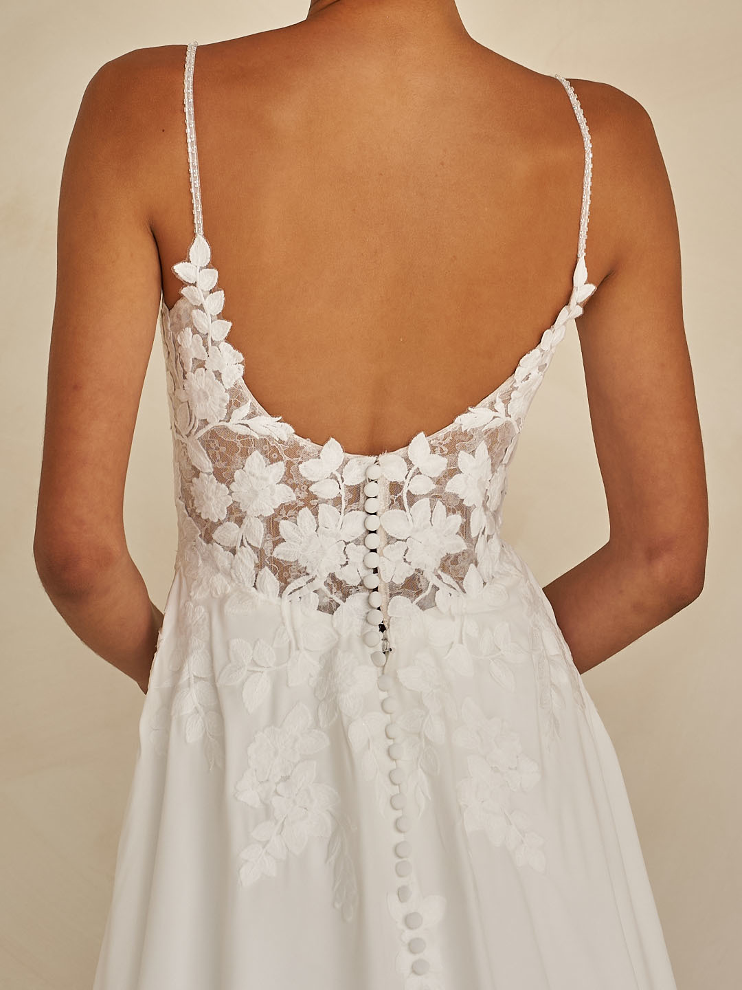 Trouwjurk met lage rug Whyte van Madi Lane. Achteraanzicht van het see-through kanten lijfje met picpac knoopjes.