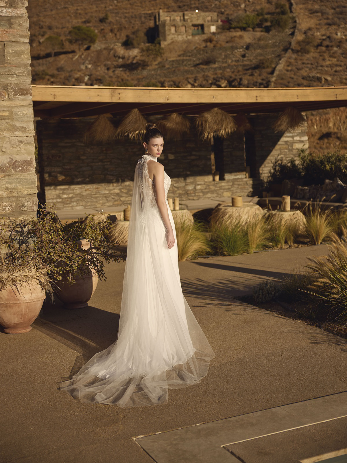 Trouwjurk Helmi van Modeca met hoge hals, achteraanzicht van de tule cape en de open rug met kant.