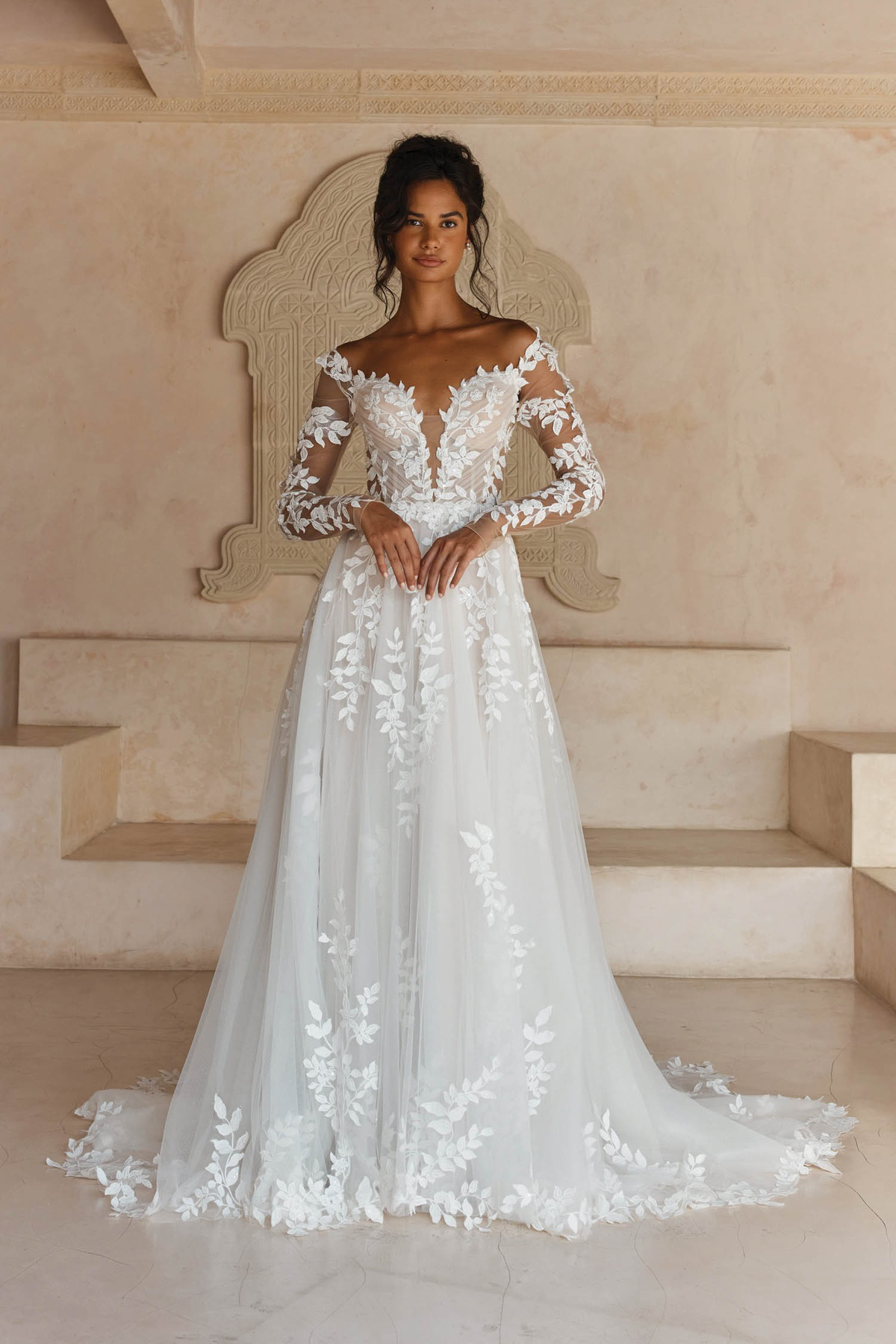 A-lijn trouwjurk Landon van Madi Lane, vooraanzicht met off-shoulder V-hals en see-through mouwen met bladkant.