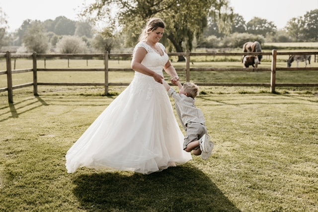 real bride anouk coopmans in een romantische a-lijn trouwjurk spelend met haar kindje in een landelijke setting