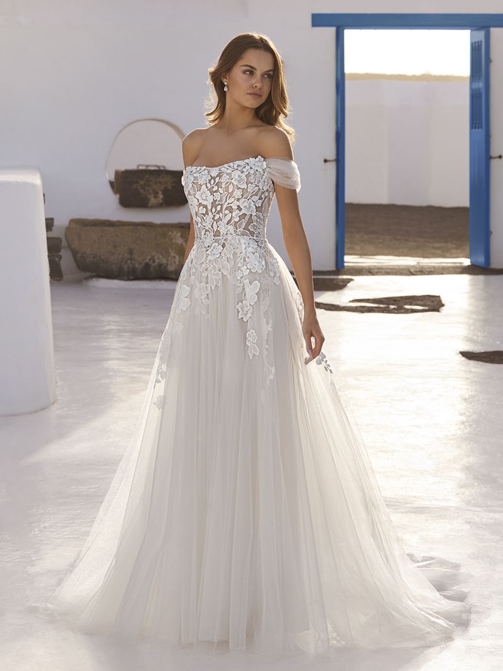 A-lijn trouwjurk Enola van Love by Enzoani in vooraanzicht met een off-shoulder halslijn en een see-through kanten lijfje.