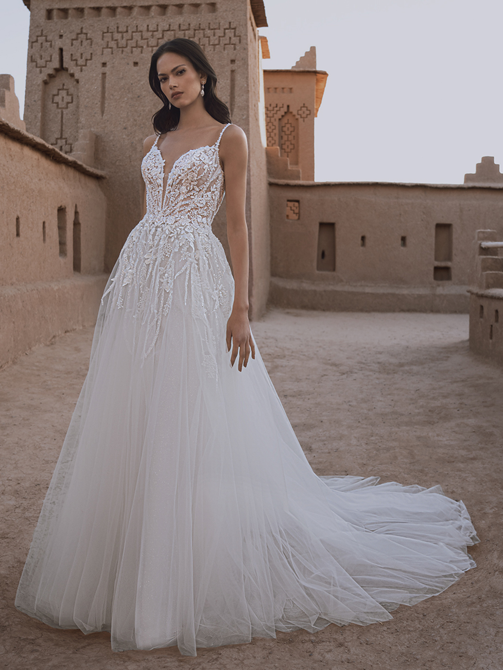 A-lijn trouwjurk Tillie van Blue by Enzoani met V-hals. Vooraanzicht van het kanten see-through lijfje en de glitter tule rok.