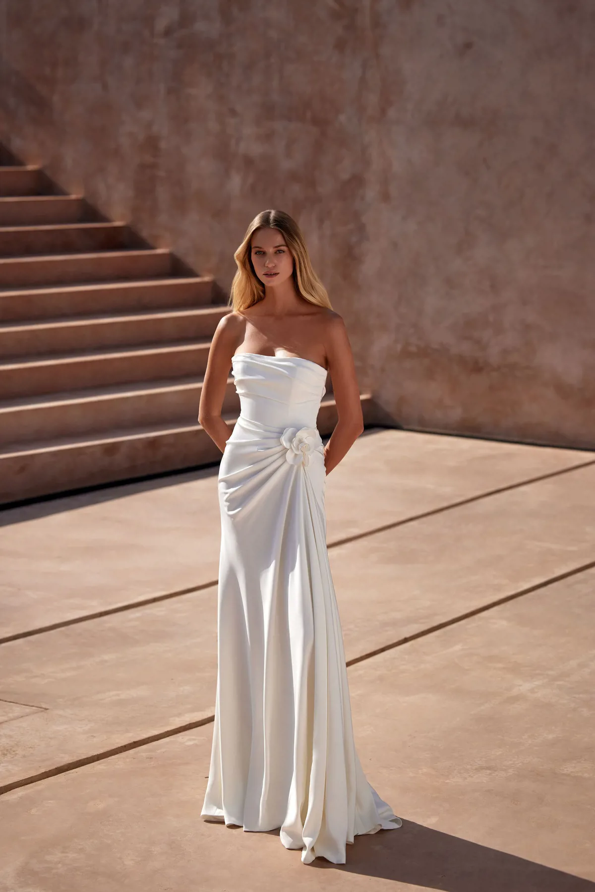 Strapless trouwjurk Lewis van Milla Nova LR in vooraanzicht met draperie en bloemdetail. Exclusief bij Bruidshuis Diana.