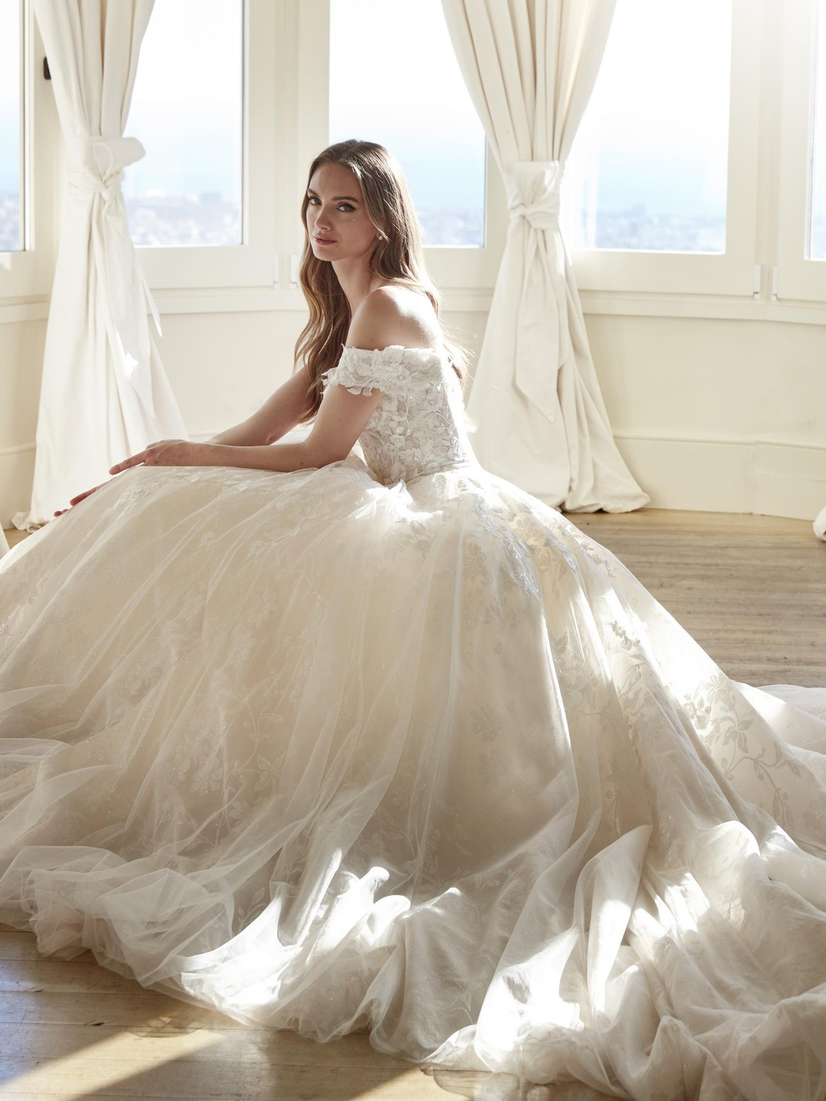 Off-shoulder prinsessen trouwjurk Juddy van San Patrick. Romantische bruidsjurk met een kanten lijfje en wijde glitterrok.