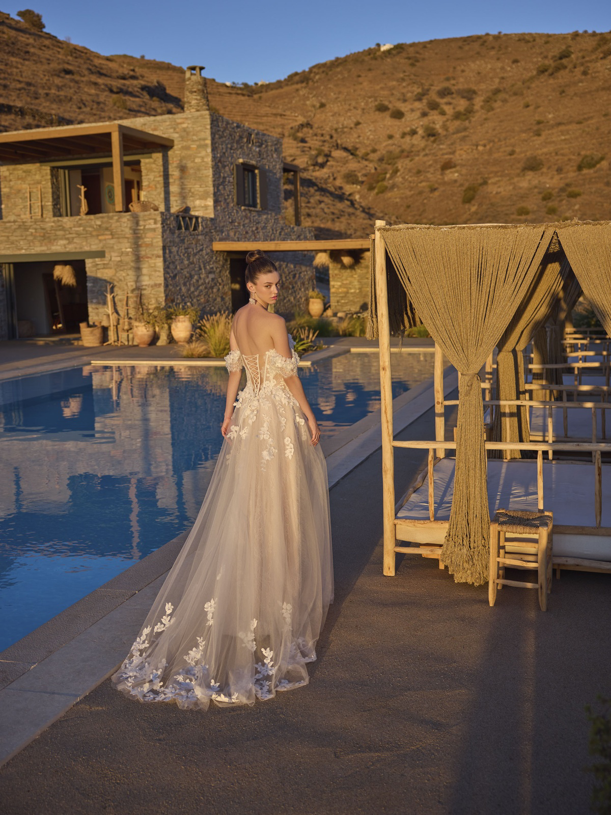 A-lijn trouwjurk Halia van Modeca met off-shoulder bandjes. Achteraanzicht van het romantische korsetlijfje en 3D kant.