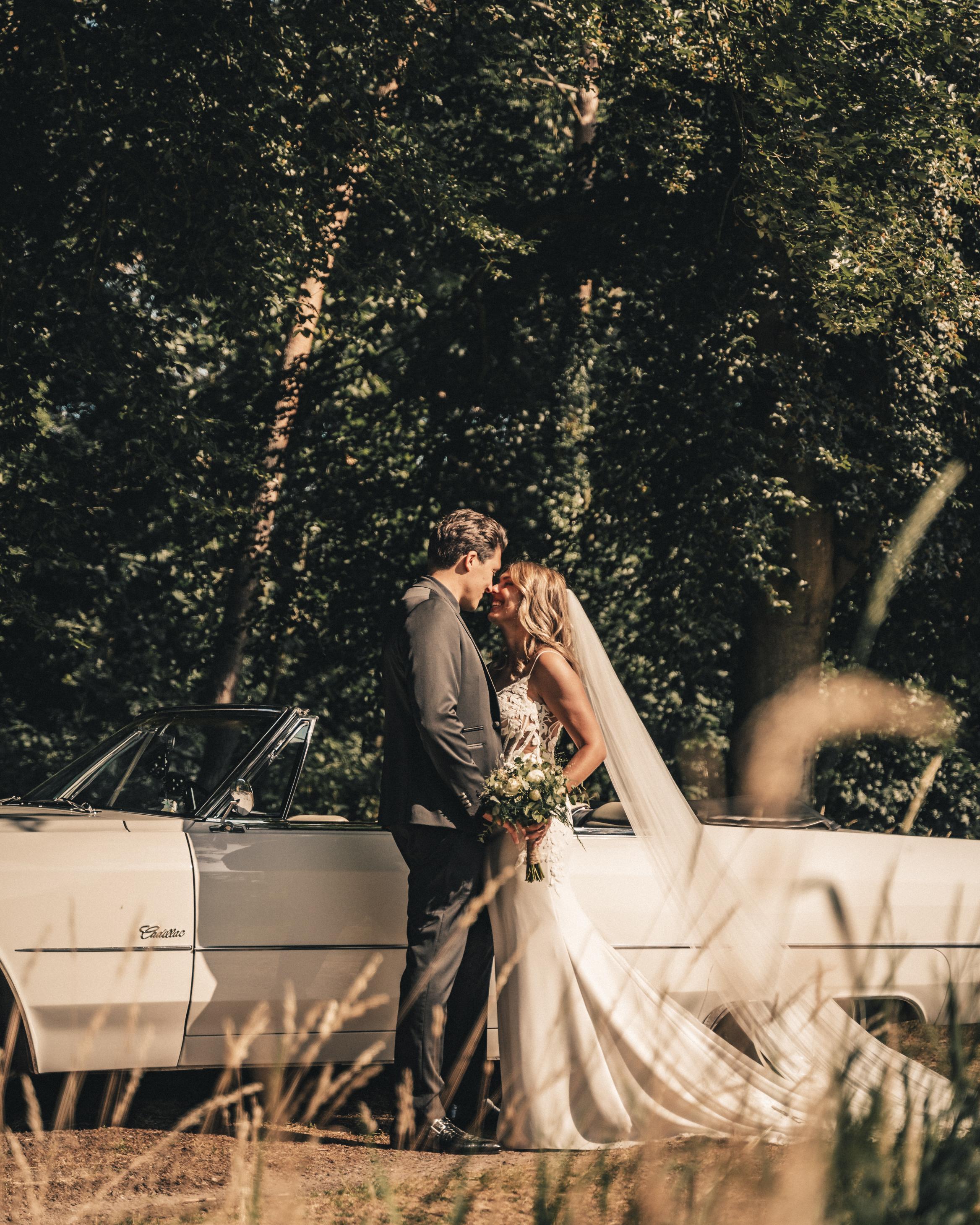jaimy in een trouwjurk bij een auto