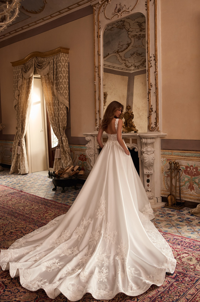 A-lijn trouwjurk Tia van Blue by Enzoani. Achteraanzicht van de lage rug en satijnen rok met lange kanten sleep en zakken.