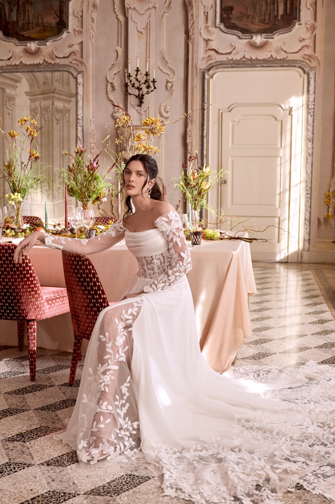 Off-shoulder trouwjurk 88480 van Justin Alexander met split. Vooraanzicht van de A-lijn met see-through kanten mouwen.