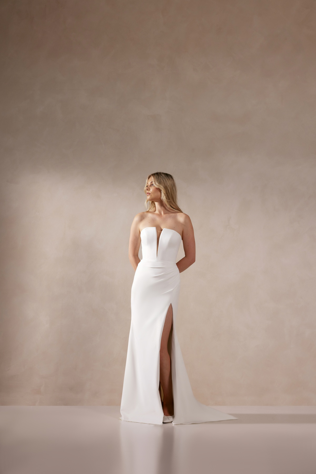 Trouwjurk met split Deva van Adore. Vooraanzicht van de strapless, minimalistische bruidsjurk met diepe V-hals.