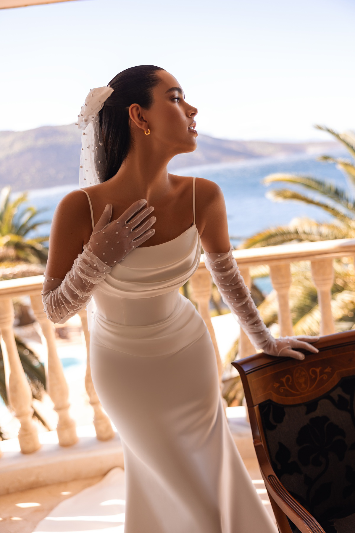 Aangesloten trouwjurk 8250 van Cosmobella in zijaanzicht, met een gedrapeerd lijfje en fijne schouderbandjes.