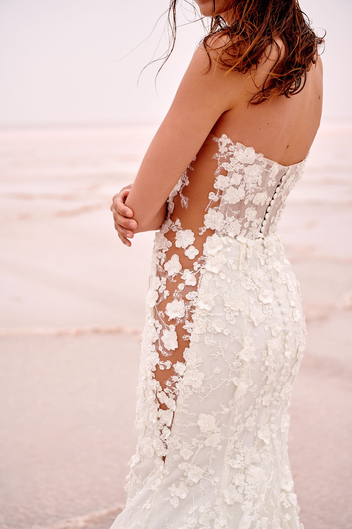 Trouwjurk met 3D kant London van Jeune by Madi Lane, zijaanzicht van de see-through zijkant en picpac knoopjes op de rug.