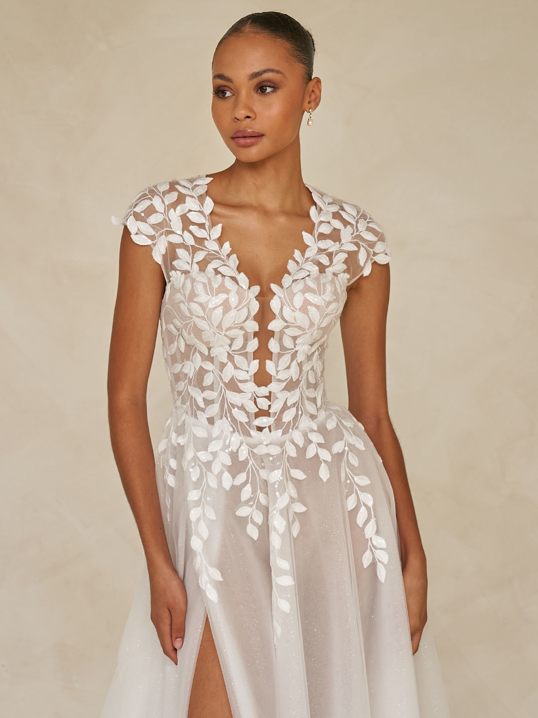 Trouwjurk Whitley van Madi Lane met diepe V-hals en bladmotief. Vooraanzicht van de flowy glittertule rok met split.