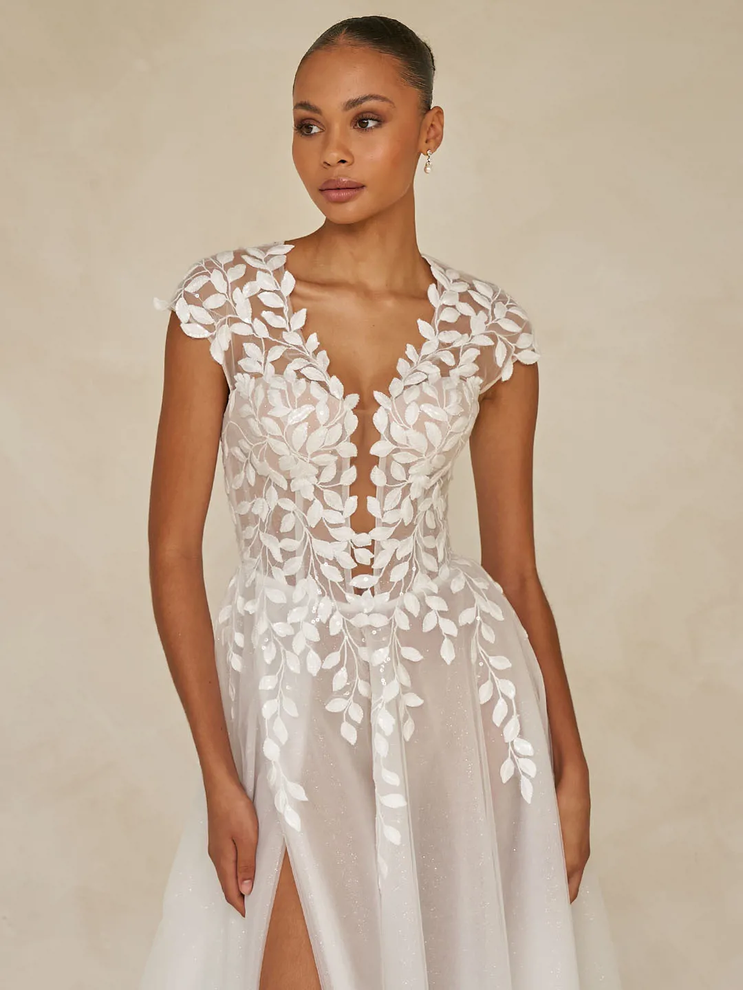 Trouwjurk Whitley van Madi Lane met diepe V-hals en bladmotief. Vooraanzicht van de flowy glittertule rok met split.