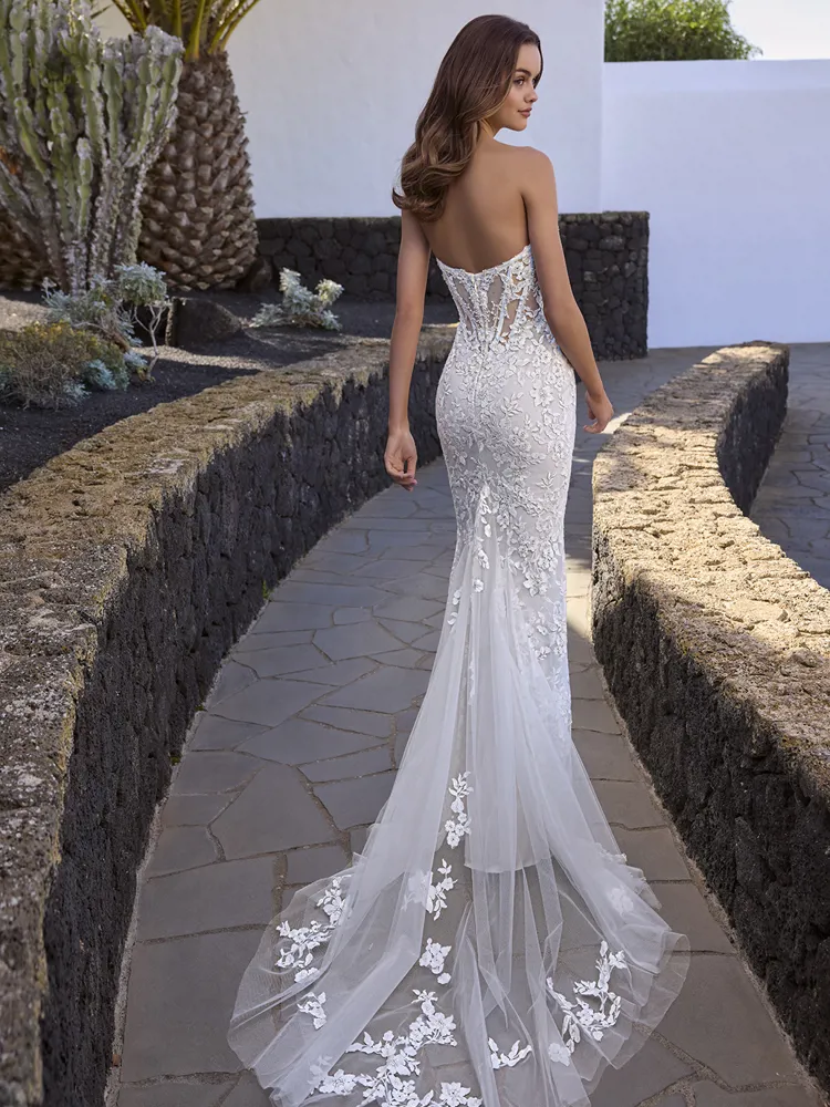 Zeemeermin trouwjurk Estrella van Love by Enzoani. Achteraanzicht met een lage rug, see-through lijfje met baleinen en tule sleep.