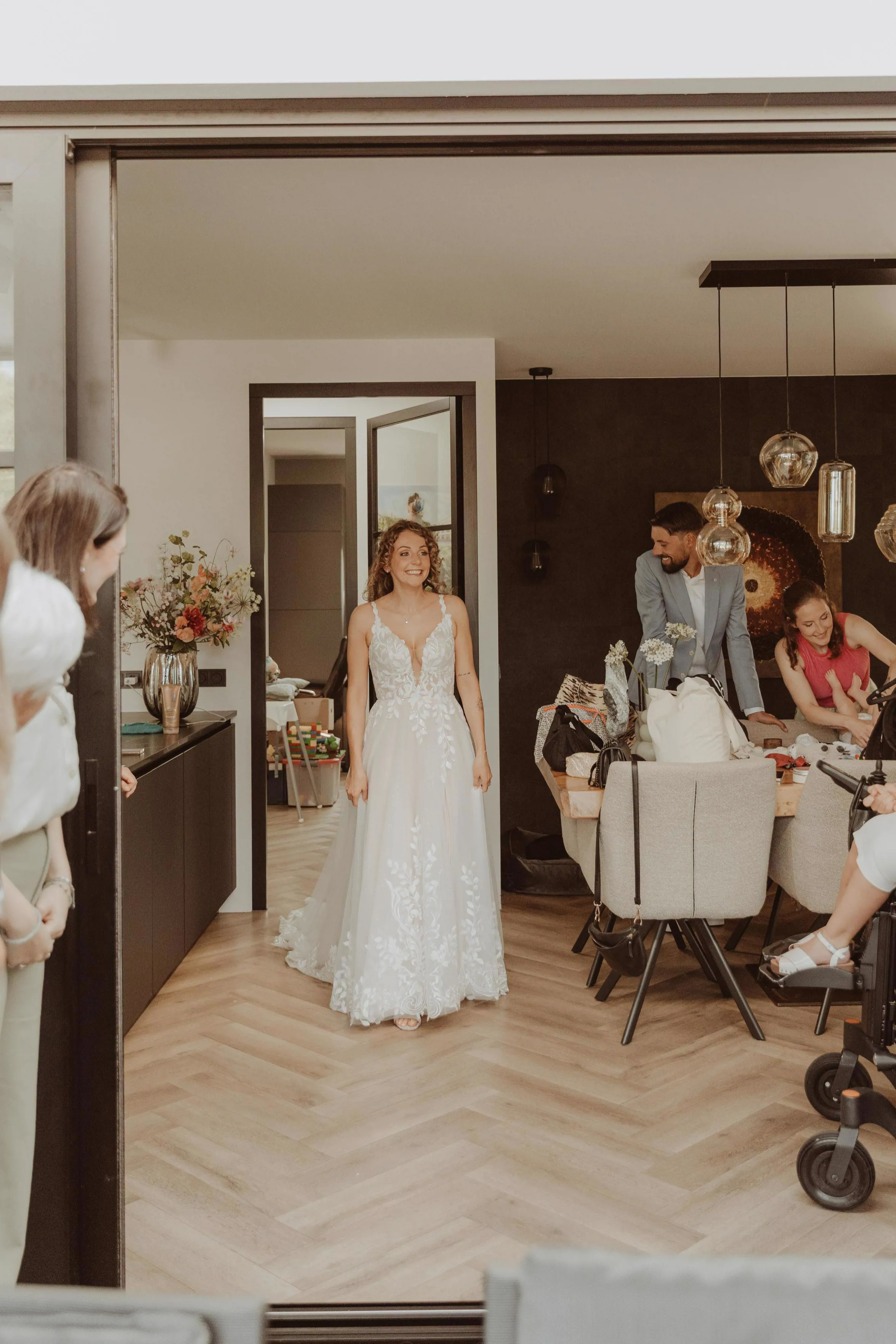 real bride stephanie van der linden – van der heijden – romantische A-lijn trouwjurk met diep kanten lijfje – Stephanie straalt tijdens haar first look binnen terwijl familie en vrienden ontroerd toekijken
