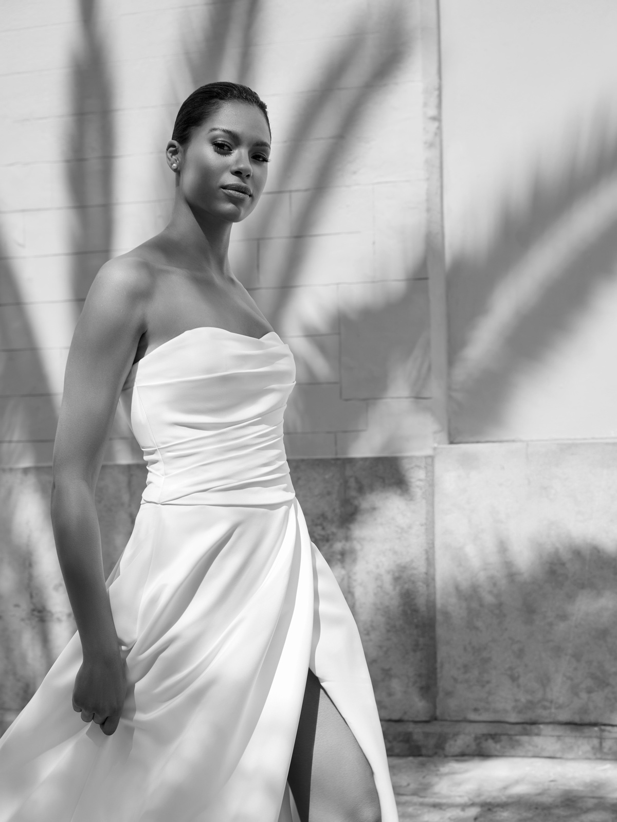 Strapless trouwjurk Easthar van White one. Zijaanzicht van de satijnen A-lijn jurk met gedrapeerd lijfje en een hoge split.