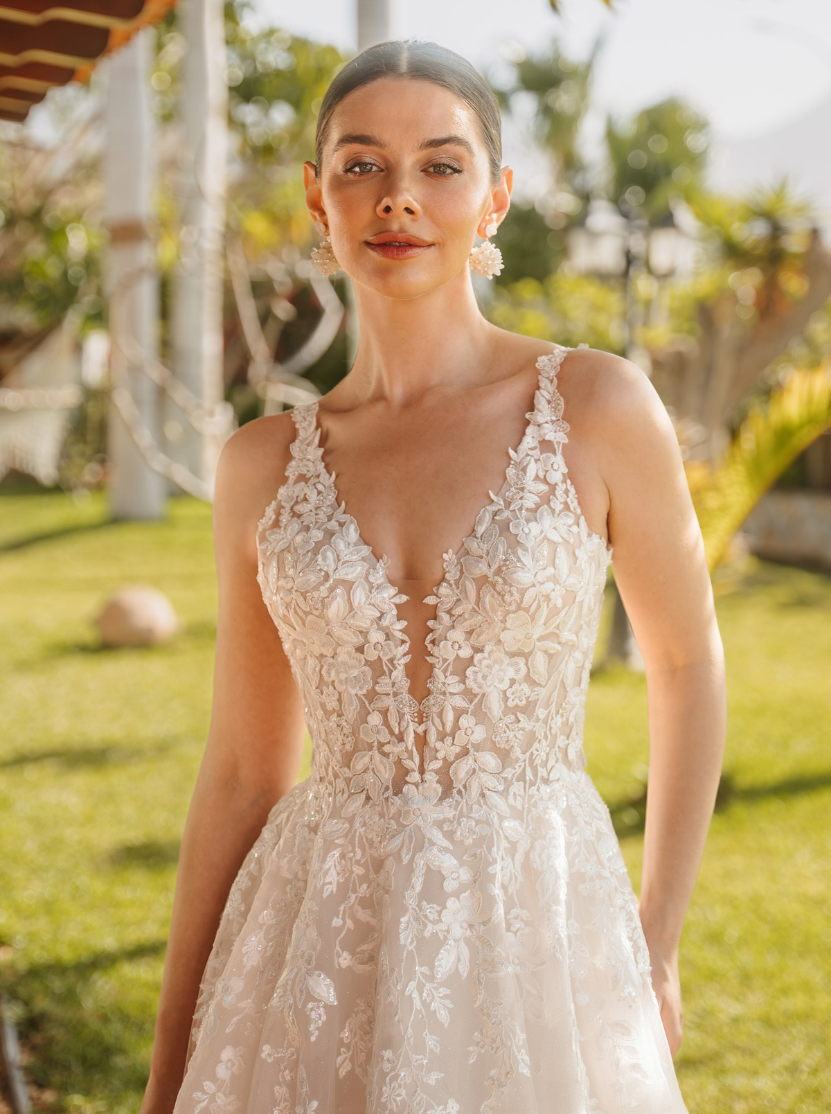 Trouwjurk met V-hals Diane Legrand 2600. Close-up van het kanten lijfje met bloemenapplicaties en see-through detail.